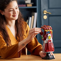 A girl with Red Marvel Infinity Saga Nano Gauntlet shown on  bliebackground.
Features colorful Infinity Stones and detailed metallic-style accents.
Mounted on a sturdy black display stand with a Marvel plaque.
Perfect for collectors and superhero-themed displays.