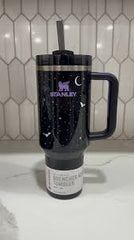 Black insulated tumbler with a design on a white surface