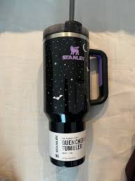 Black tumbler with a design on a white surface