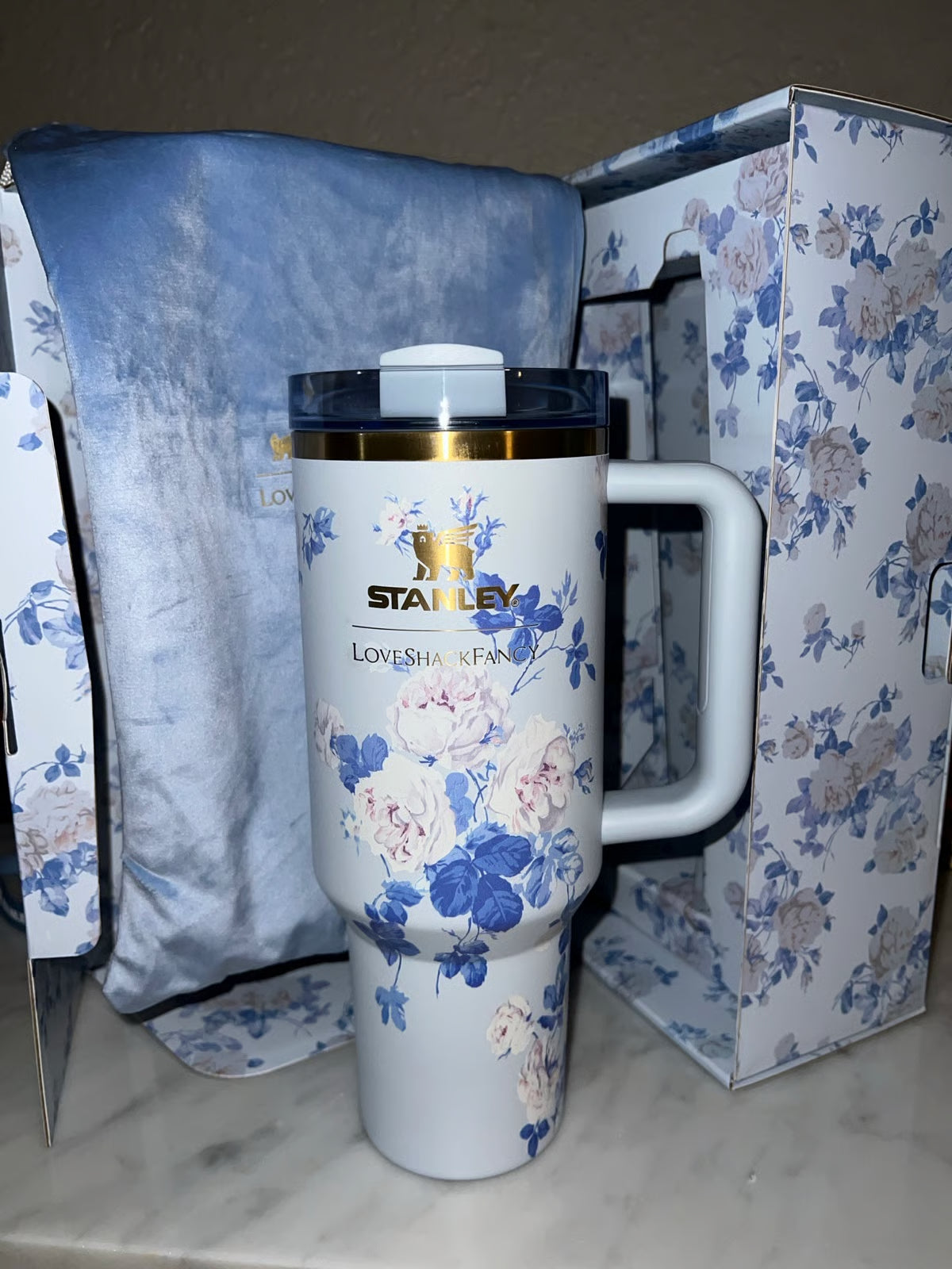 Floral-patterned travel mug with 'Stanley' branding on a floral-patterned surface.