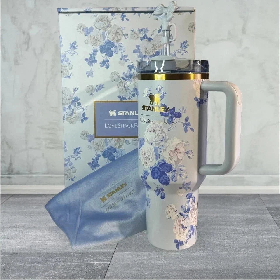 Floral-patterned travel mug with matching sleeve and box on a marble surface