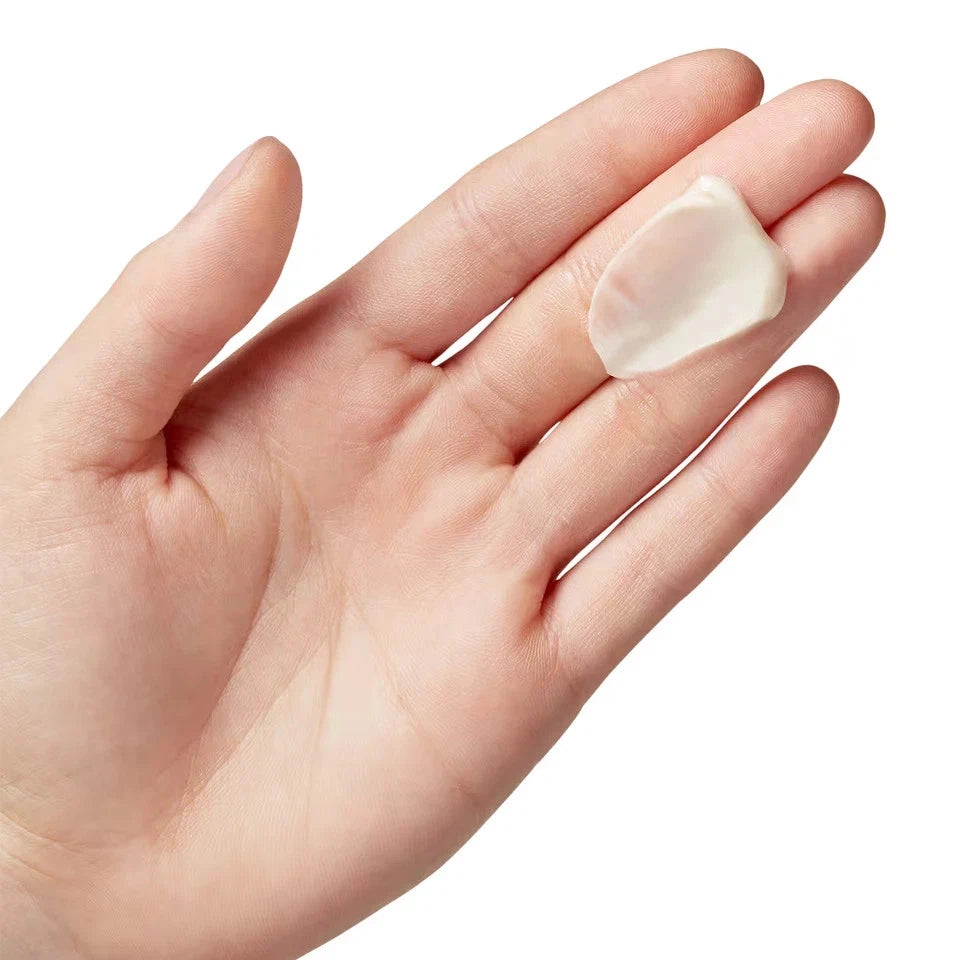 Hand holding a small, smooth stone against a white background