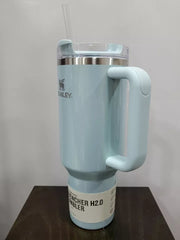 Light blue Stanley tumbler with handle on a wooden surface