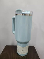Light blue travel mug with a handle on a wooden surface against a white background