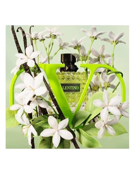 Perfume bottle with white flowers and vanilla beans on a light green background