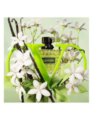 Perfume bottle with white flowers and vanilla beans on a light green background