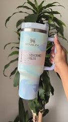 Person holding a branded tumbler with a plant in the background