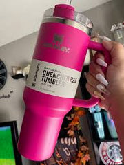 Person holding a pink insulated tumbler with a brand logo in an indoor setting