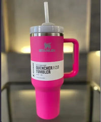 Pink Stanley Quencher H2.0 tumbler with a straw on a reflective surface.