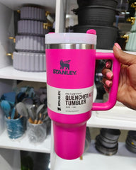 Pink Stanley tumbler held by a hand with a blurred background