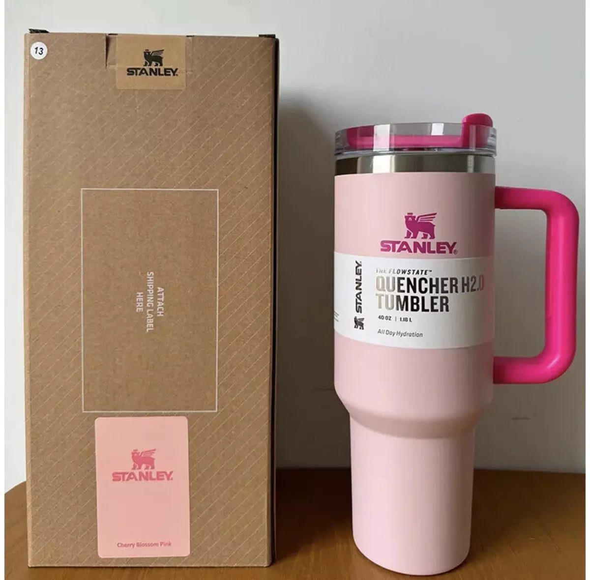 Pink Stanley tumbler with a matching box on a wooden surface.