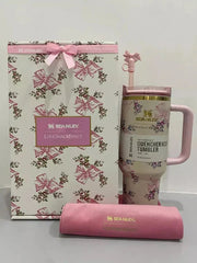 Pink floral Stanley tumbler with matching gift bag and sleeve on a white background