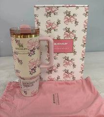 Pink floral Stanley tumbler with matching pouch and floral-patterned box on a gray background
