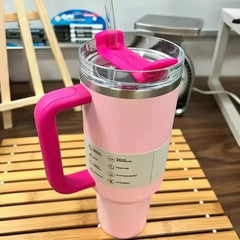 Pink insulated tumbler with a handle on a wooden surface