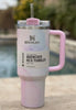 Pink marbled tumbler with handle and straw lid on a wooden surface, Stanley branding visible.