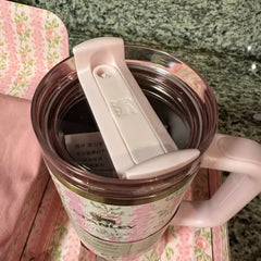 Pink tumbler with floral design on a floral cushion