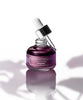 Purple skincare serum bottle with dropper on a white background