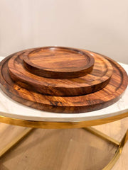 Set of three wooden trays on a glass table with a gold base.
