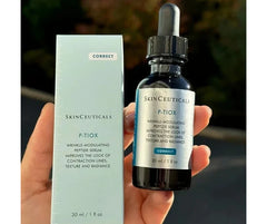 SkinCeuticals P.TiOX skincare serum bottle and packaging held in a hand with a blurred background.