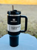 Stanley Quencher H2.0 tumbler with straw on a blue surface outdoors