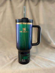 Green Stanley travel mug with a black handle on a beige fabric background