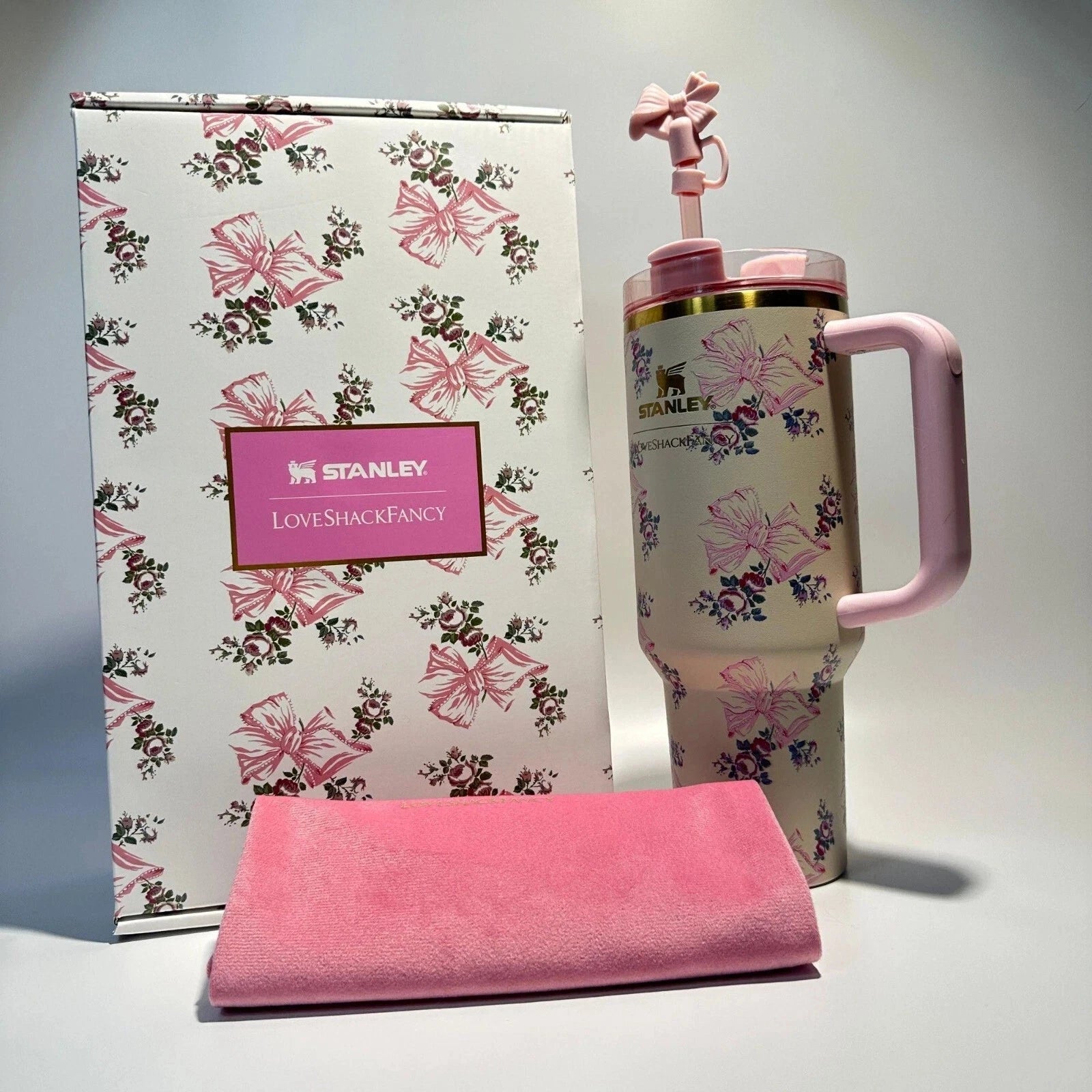 Stanley branded pink and floral-patterned mug with matching towel on a light gray background
