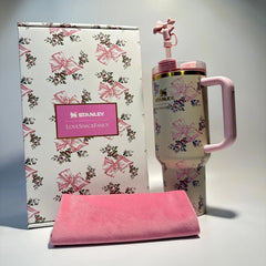 Stanley branded pink and floral-patterned mug with matching towel on a light gray background