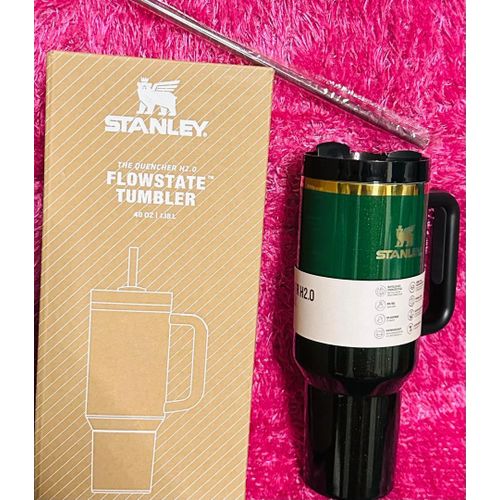 Stanley tumbler with packaging on a pink textured background