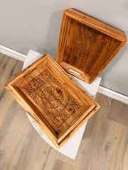 Two wooden trays with intricate carvings on a white surface.