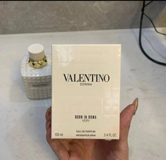 Valentino Donna perfume box held by a hand on a marble surface