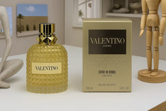 Valentino perfume bottle and packaging on a table with decorative items in the background