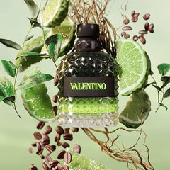 Valentino perfume bottle surrounded by lime slices and leaves on a green background