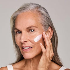 Woman applying Estée Lauder Resilience Multi‑Effect Night cream to cheek