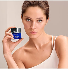 Woman holding a La Prairie skincare product against a neutral background