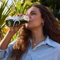 Woman drinking AG1 Greens Powder Supplement for daily nutritional coverage and gut health support outdoors